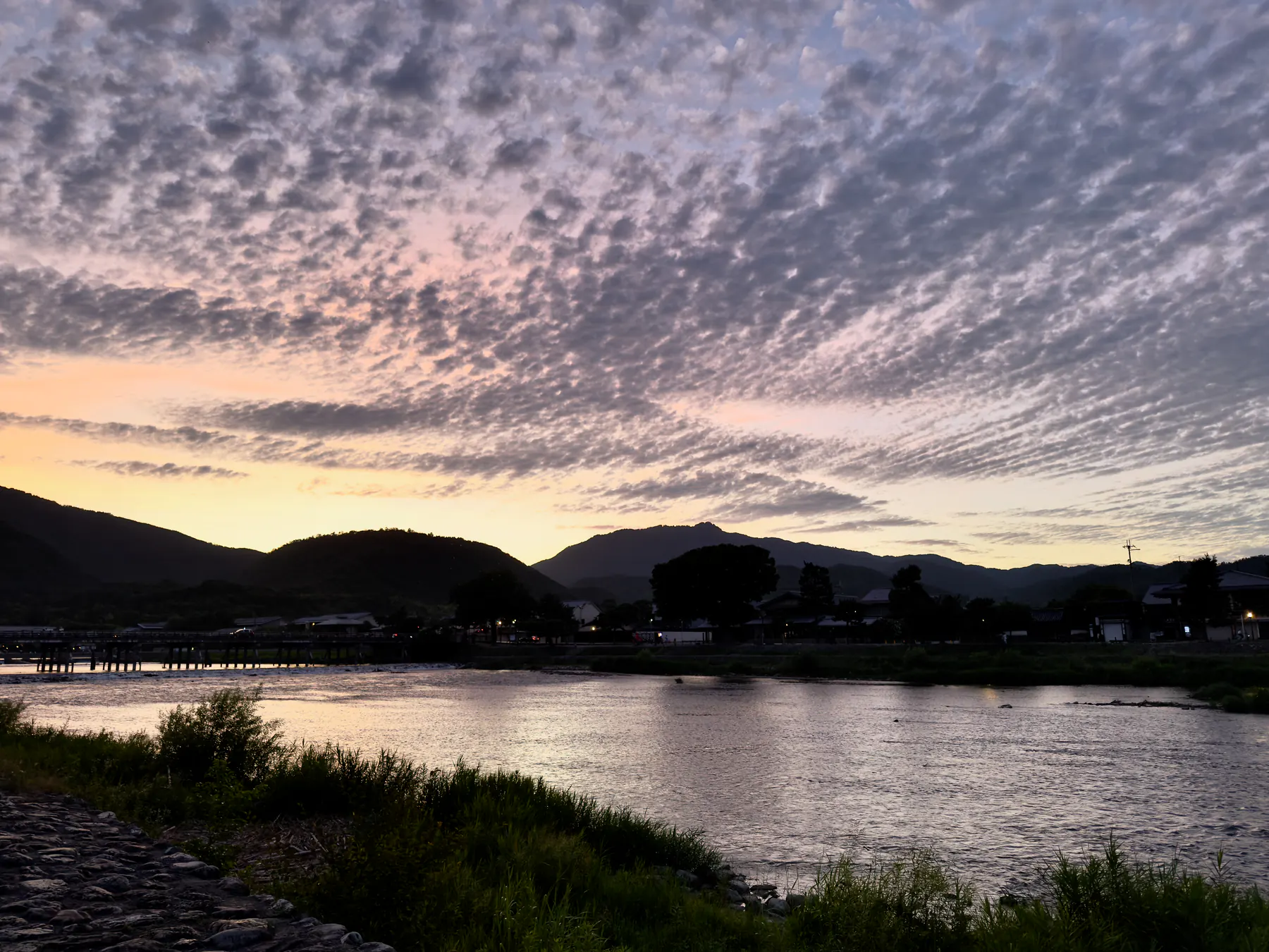 the Katsura river and the Togetsukyō bridge at dusk, seen from the bank
