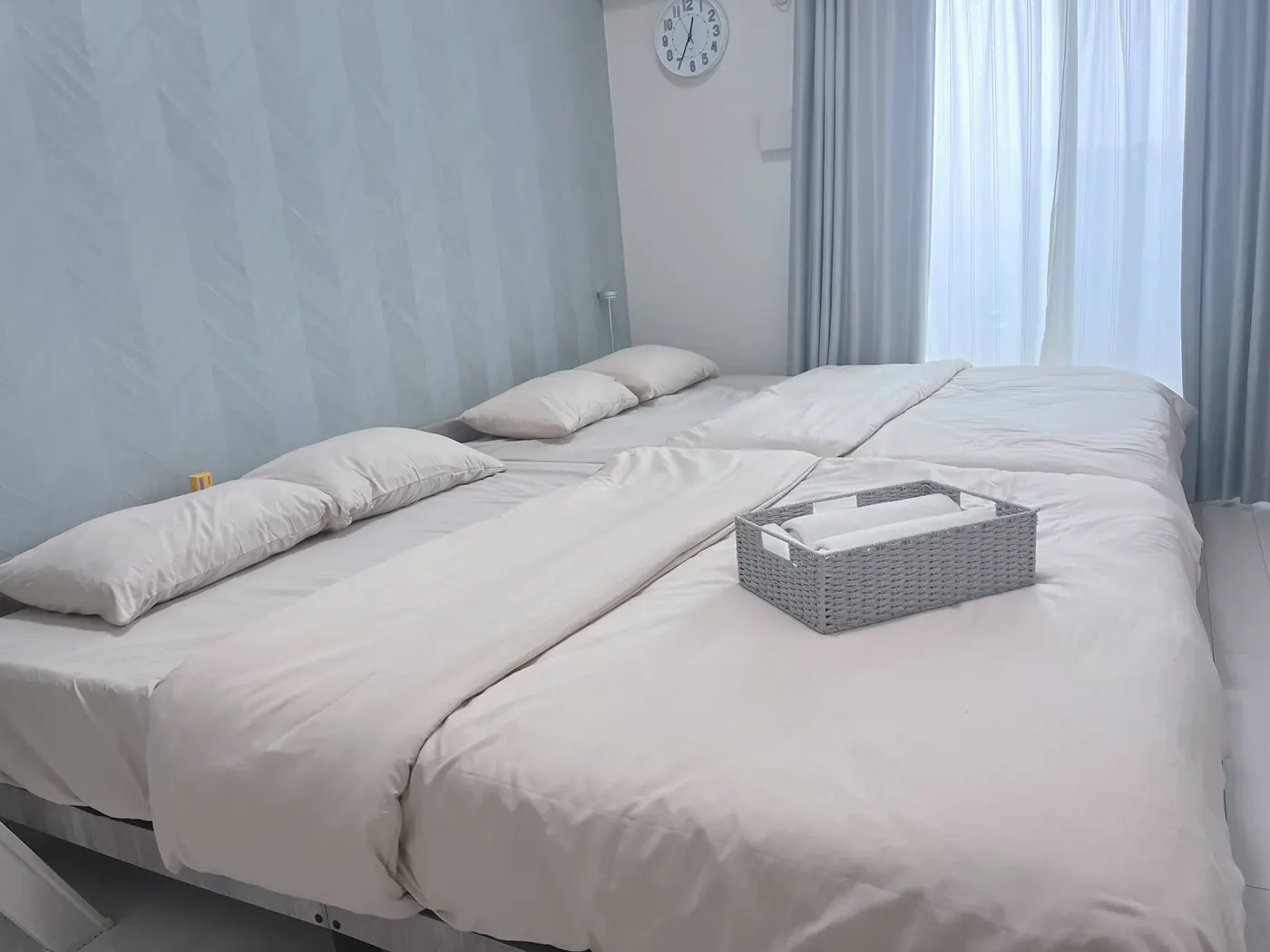 a bedroom: two beds, light through the net curtain